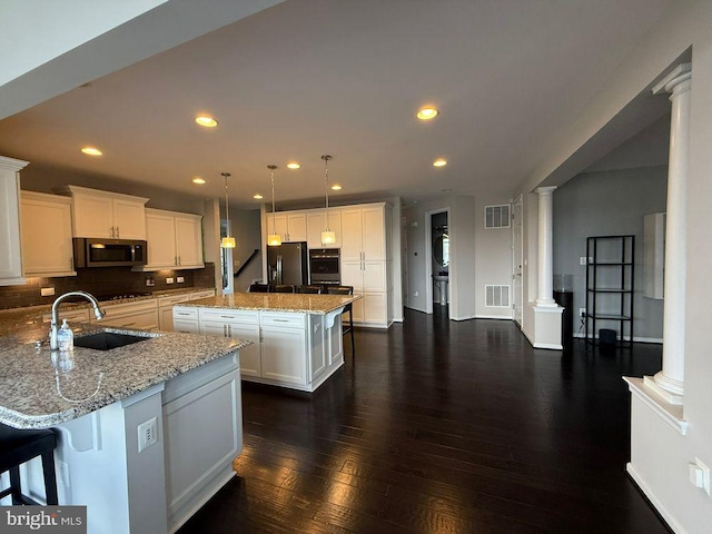 kitchen featuring ornate columns, a kitchen island, sink, and stainless steel fridge