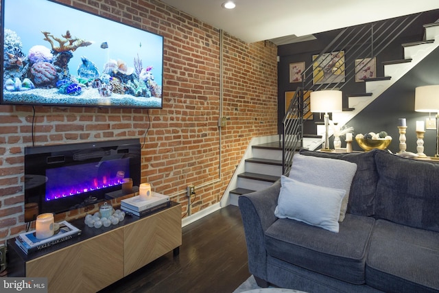 living room with brick wall, hardwood / wood-style floors, and a brick fireplace