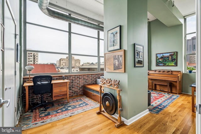 office with wood-type flooring and brick wall