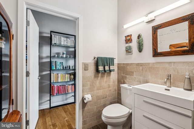 bathroom featuring hardwood / wood-style flooring, vanity, toilet, and tile walls