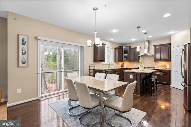 dining space with sink, a chandelier, and dark hardwood / wood-style floors