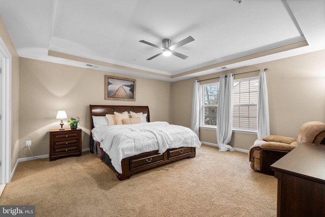 carpeted bedroom with a tray ceiling, ornamental molding, and ceiling fan