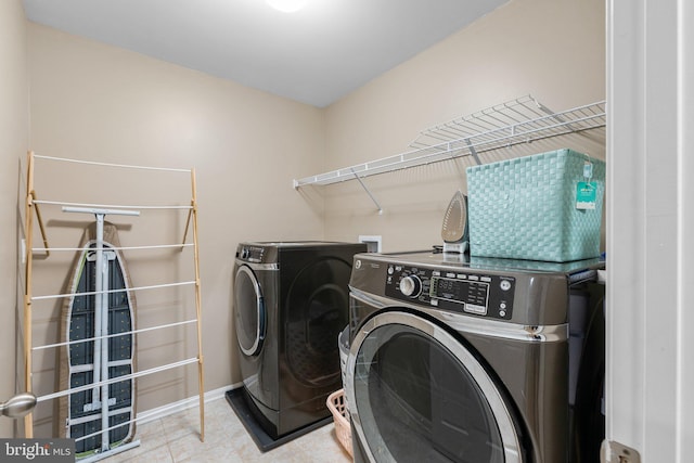 laundry area with washing machine and clothes dryer and light tile patterned floors