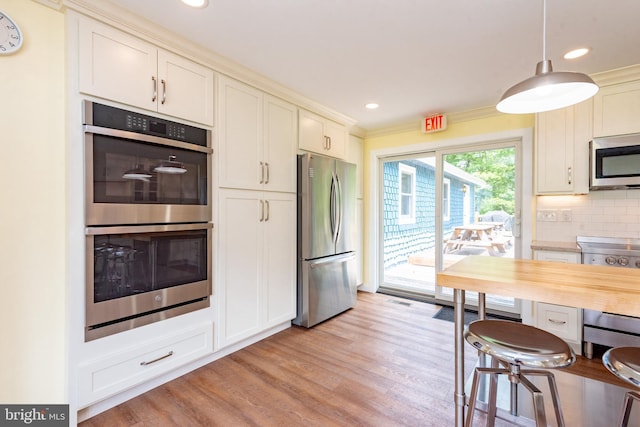 kitchen featuring stainless steel appliances, light wood finished floors, backsplash, hanging light fixtures, and recessed lighting