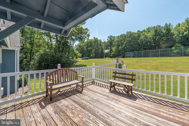 wooden terrace featuring a lawn and view of wooded area