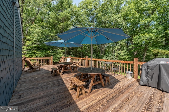 wooden deck featuring outdoor dining space, a grill, and view of scattered trees