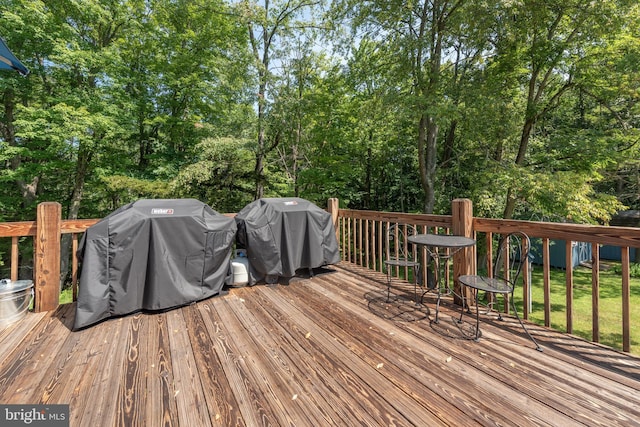 wooden deck featuring area for grilling and view of wooded area