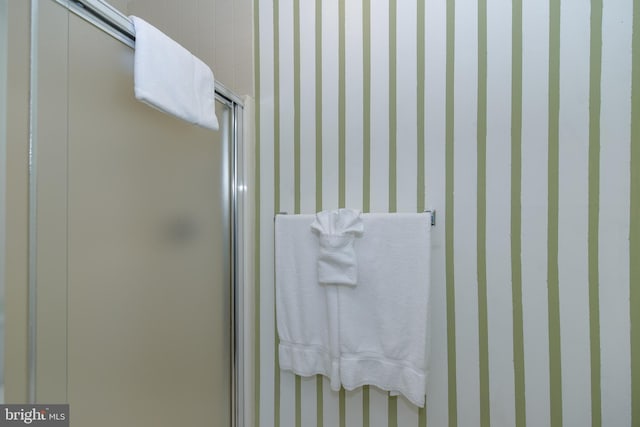 bathroom featuring wallpapered walls and a stall shower