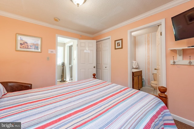 carpeted bedroom with a closet, ornamental molding, ensuite bath, baseboards, and a textured ceiling