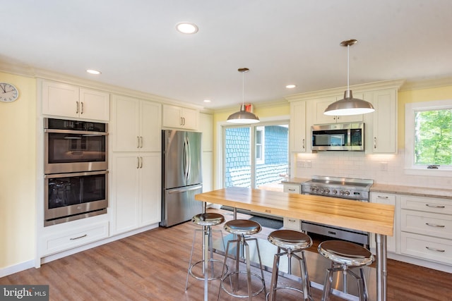 kitchen featuring appliances with stainless steel finishes, dark wood-style flooring, tasteful backsplash, butcher block countertops, and pendant lighting