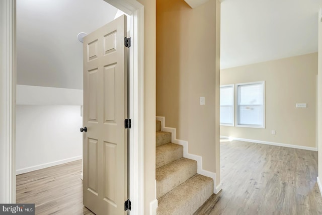 stairway with hardwood / wood-style floors and vaulted ceiling