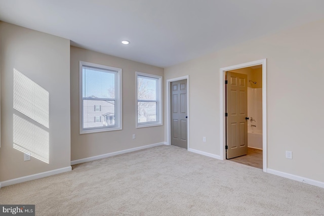 unfurnished bedroom featuring light colored carpet and connected bathroom