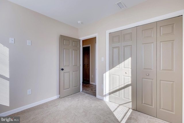 unfurnished bedroom featuring light carpet and a closet