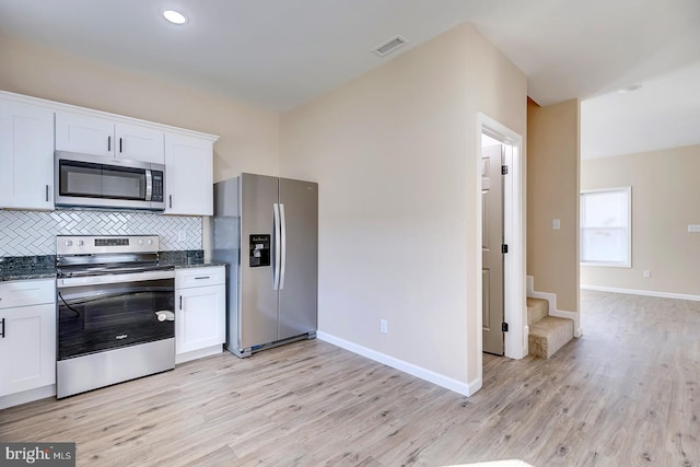 kitchen featuring white cabinetry, light wood-type flooring, tasteful backsplash, and appliances with stainless steel finishes