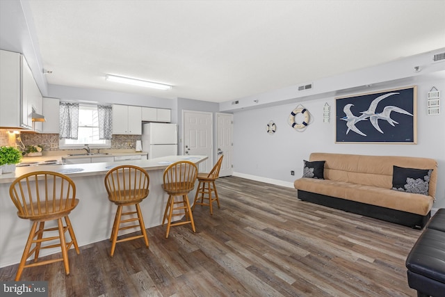 kitchen featuring sink, a breakfast bar, white refrigerator, tasteful backsplash, and white cabinets