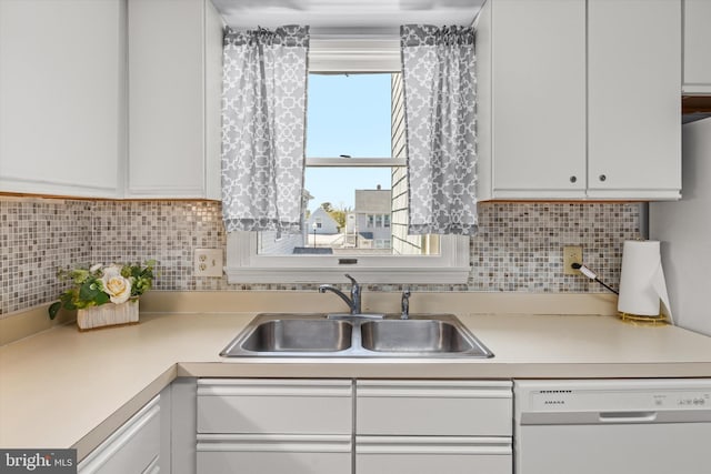 kitchen featuring white dishwasher, sink, tasteful backsplash, and white cabinets