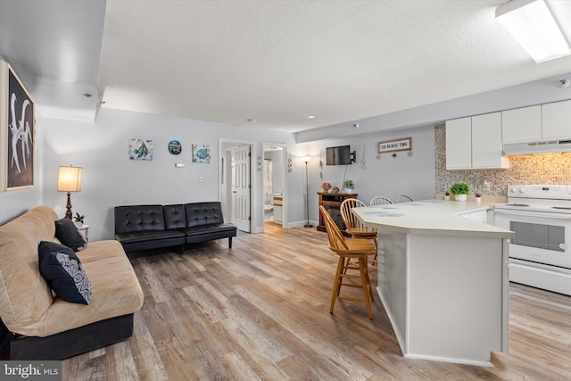 kitchen with a breakfast bar, white range with electric stovetop, white cabinets, kitchen peninsula, and light hardwood / wood-style flooring