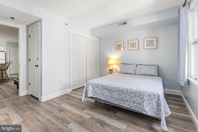 bedroom with hardwood / wood-style floors, a closet, and white fridge