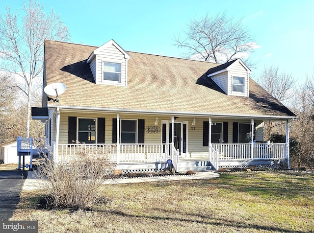 new england style home featuring a porch and a front lawn