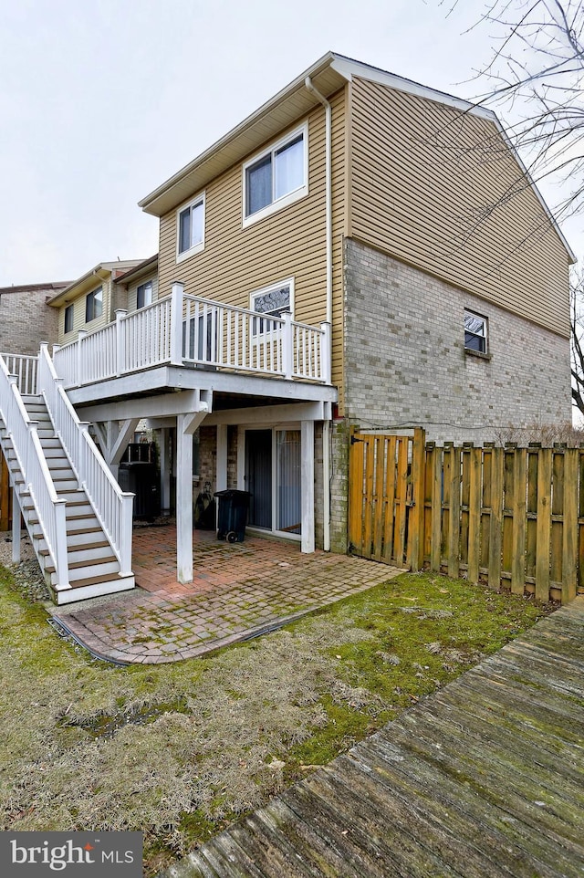 rear view of house featuring a wooden deck and a patio