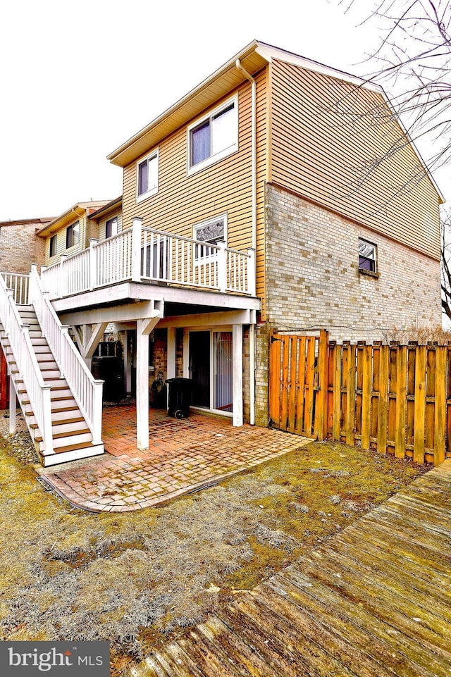 rear view of house featuring a wooden deck and a patio area