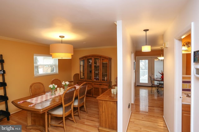 dining room featuring crown molding, light wood-type flooring, and french doors