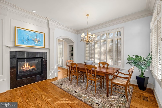 dining area with crown molding, wood-type flooring, and a tile fireplace