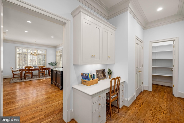 office space with ornamental molding, an inviting chandelier, and light hardwood / wood-style flooring