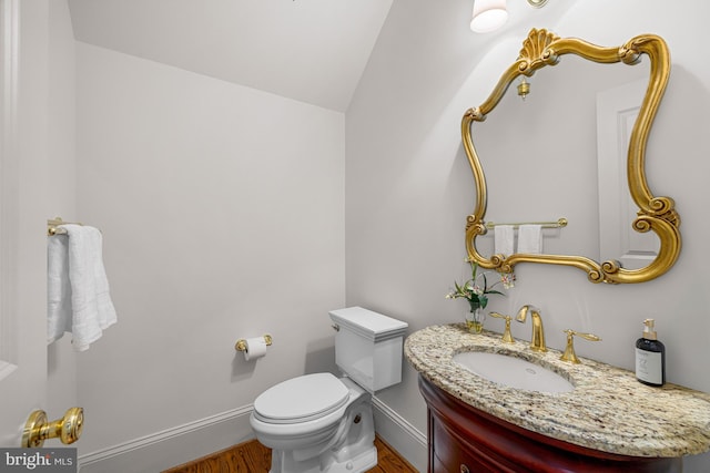 bathroom featuring vanity, hardwood / wood-style floors, lofted ceiling, and toilet