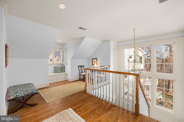 hallway with lofted ceiling, hardwood / wood-style floors, and crown molding