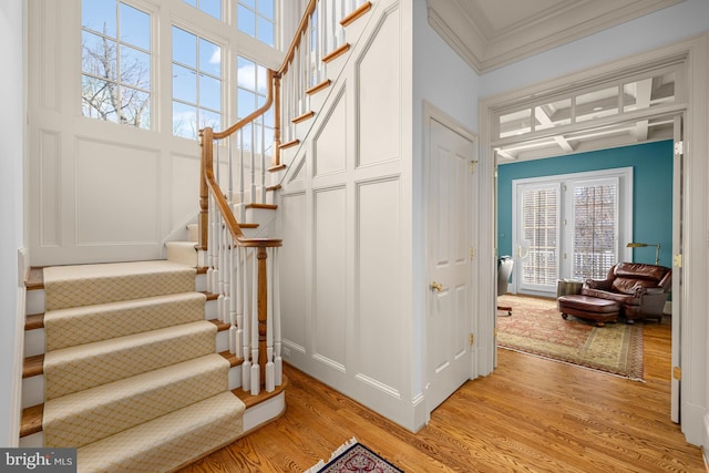 stairs with hardwood / wood-style floors and crown molding