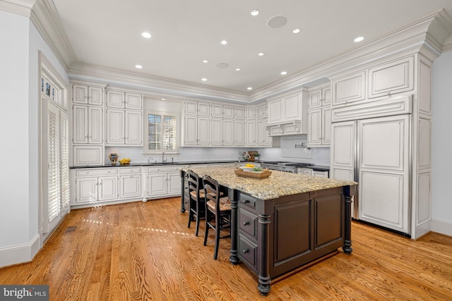 kitchen with light stone counters, a center island, white cabinets, and a breakfast bar