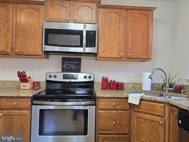 kitchen featuring sink, light stone countertops, and appliances with stainless steel finishes