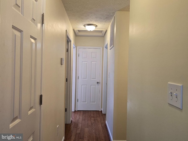 hall featuring dark wood-type flooring and a textured ceiling