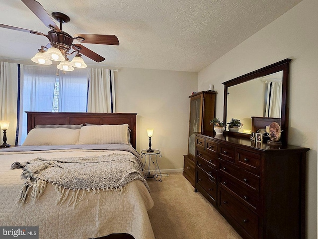 bedroom featuring ceiling fan, light colored carpet, and a textured ceiling