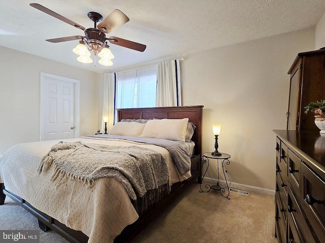 carpeted bedroom with ceiling fan and a textured ceiling