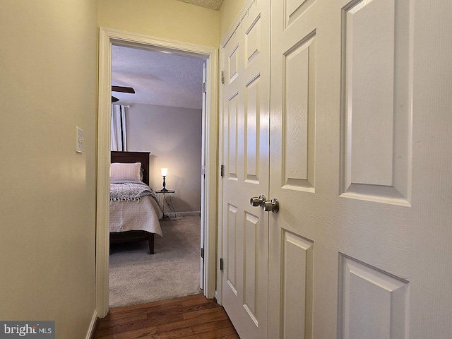 hallway featuring dark wood-type flooring and a textured ceiling