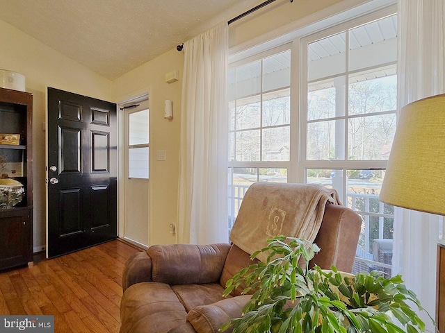 living area featuring wood-type flooring, vaulted ceiling, and a textured ceiling