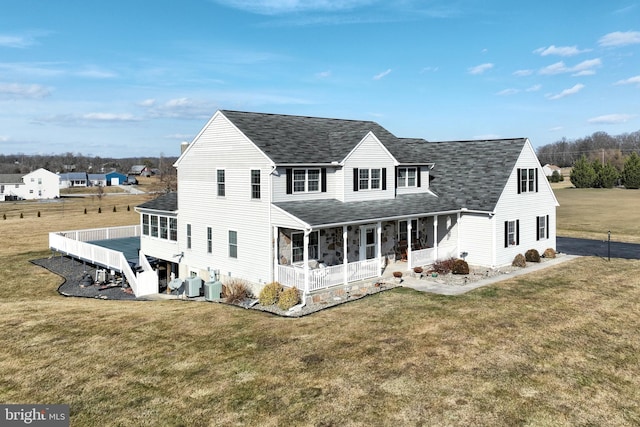 rear view of property featuring a sunroom, central AC unit, and a lawn