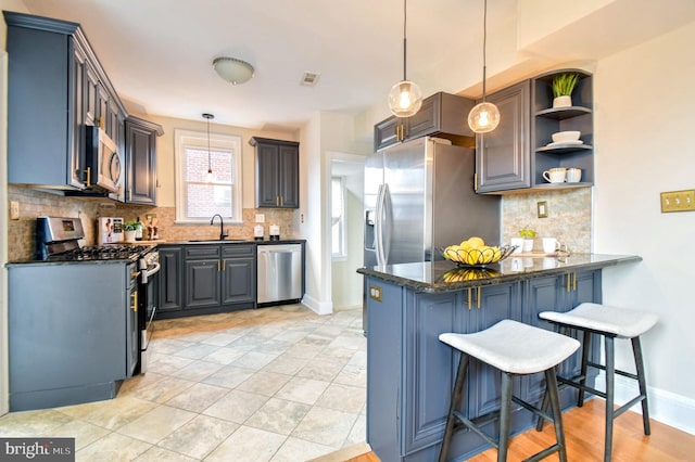 kitchen with sink, gray cabinets, stainless steel appliances, decorative light fixtures, and kitchen peninsula