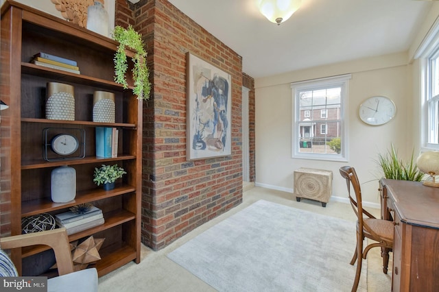 office area featuring light carpet and brick wall