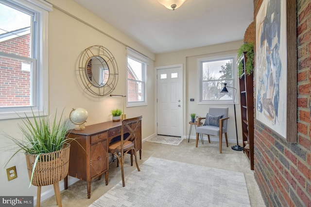 foyer featuring light colored carpet and brick wall