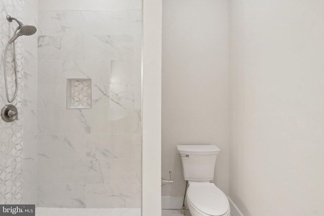 full bathroom featuring tiled shower, toilet, and baseboards