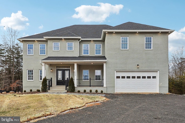 view of front of property featuring an attached garage, brick siding, a porch, and aphalt driveway