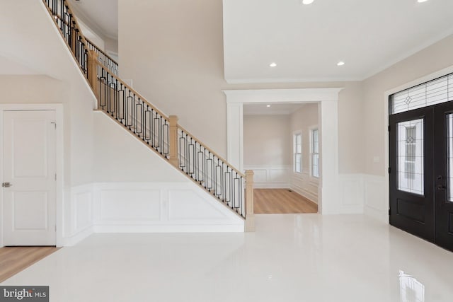 foyer entrance with french doors, a wainscoted wall, crown molding, recessed lighting, and stairs