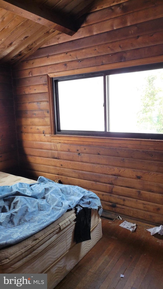 unfurnished bedroom featuring lofted ceiling with beams, hardwood / wood-style flooring, log walls, and wood ceiling