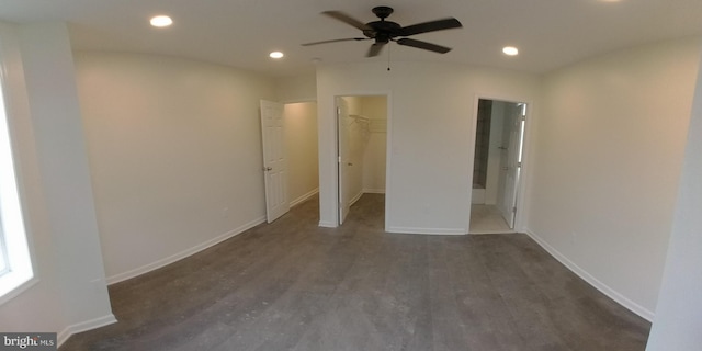 unfurnished bedroom featuring dark wood-type flooring, ceiling fan, ensuite bathroom, a spacious closet, and a closet