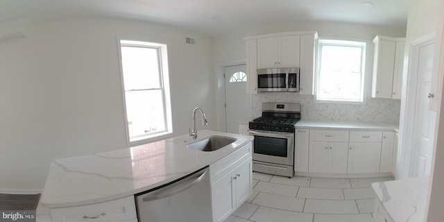 kitchen featuring white cabinetry, stainless steel appliances, light stone countertops, and sink