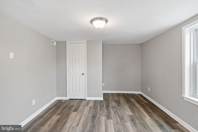 spare room with dark wood-type flooring and plenty of natural light