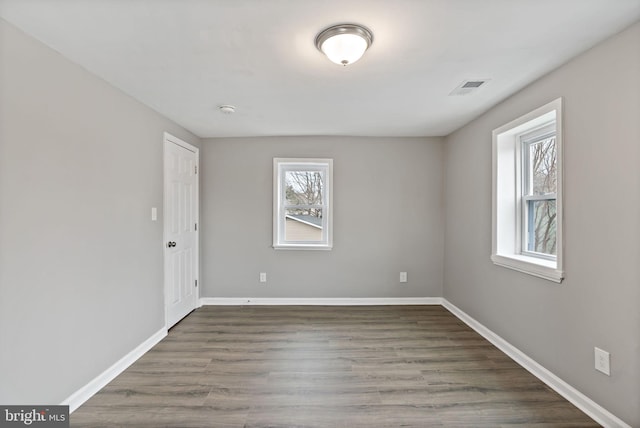 spare room featuring a healthy amount of sunlight and dark hardwood / wood-style flooring